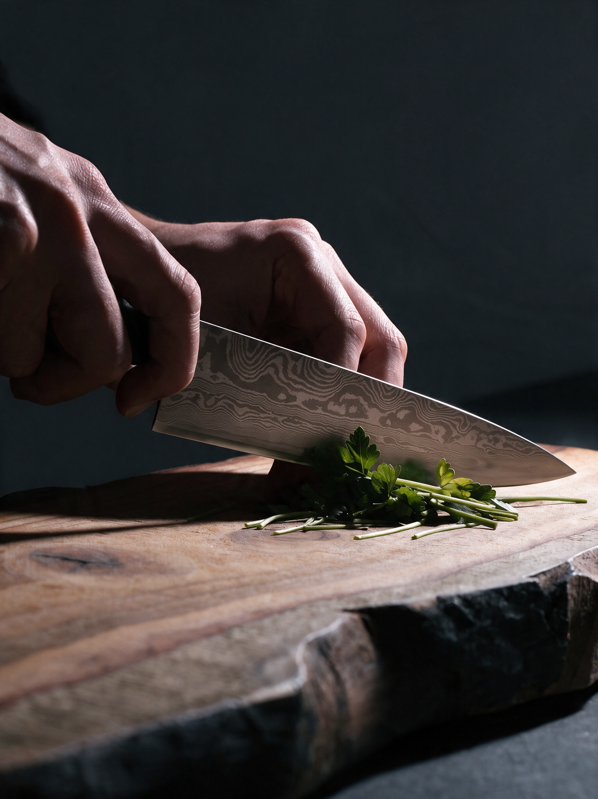 Le Gyuto 200 en usage, tranchant des herbes sur une planche en bois brut