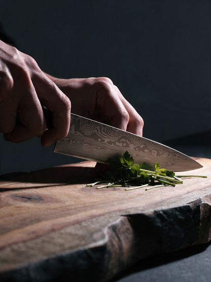 Le Gyuto 200 en usage, tranchant des herbes sur une planche en bois brut